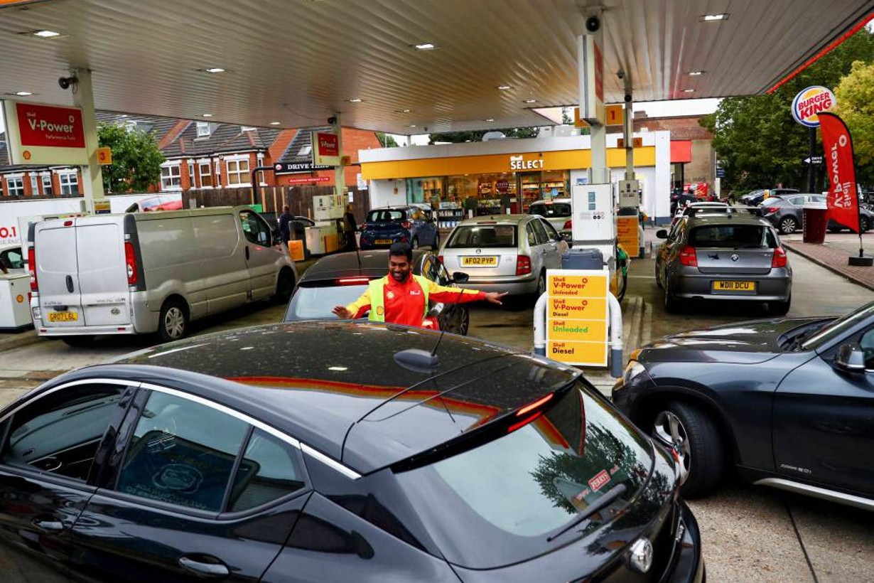 Un empleado guiaba a vehículos a la entrada de una gasolinera en Londres / Hannah Mckay (Reuters).