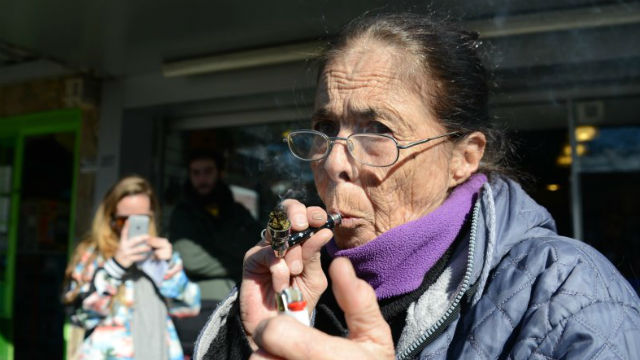 Una mujer fuma, a la salida de una farmacia.